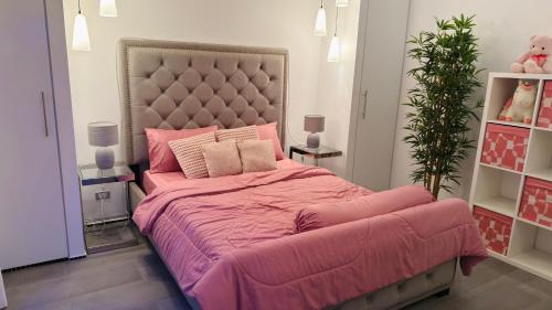 a bedroom with a large pink bed with a large headboard at Lagoon Poolvillas Pattaya in Ban Huai Yai