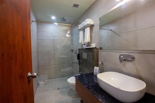 a bathroom with a sink and a toilet and a shower at Hotel Maas Residency in Māvelikara