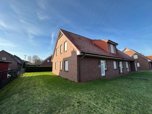a brick house on a grassy yard at Möwennest in Norden