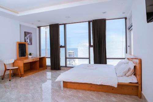 a bedroom with a bed and a desk and windows at The July - Coliving by Kegotel in Vung Tau