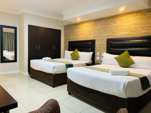 a hotel room with two beds and a desk at Bayside Hotel 97 Russell Street in Durban