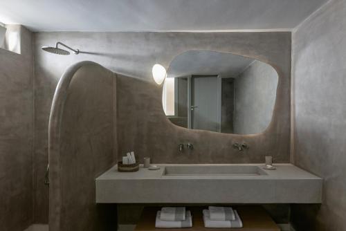 a bathroom with a sink and a large mirror at Apanemo Private Suites in Akrotiri