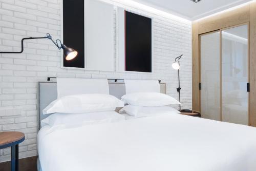 a white bedroom with a large bed and a table at The Corner Hotel in Barcelona