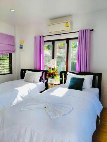 two beds in a room with purple curtains at Baan Golden Resort & Residences in Sam Roi Yot