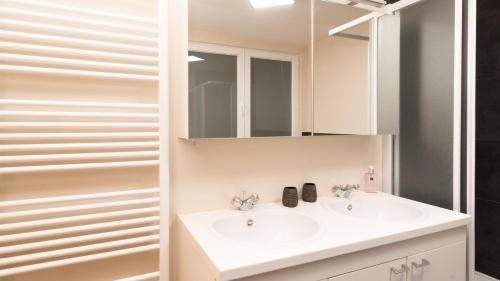 a bathroom with a white sink and a mirror at Appartement de Panne zeedijk in De Panne