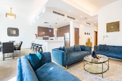 a living room with blue couches and a table at Livin' Holidays - 3BR - Family Friendly Townhouse w Private Pool in Ras al Khaimah