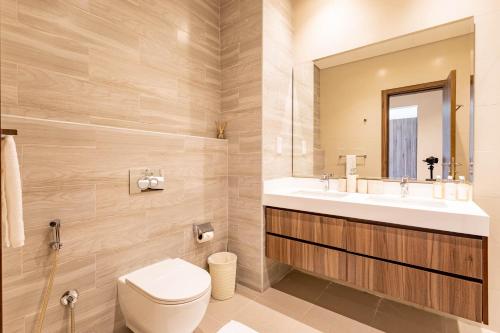 a bathroom with a toilet and a sink and a mirror at Livin' Holidays - 3BR - Family Friendly Townhouse w Private Pool in Ras al Khaimah