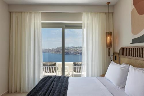 a bedroom with a bed and a view of the ocean at Apanemo Private Suites in Akrotiri