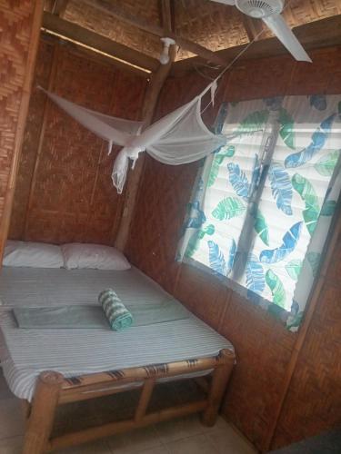 a bed in a room with a window at Enas Cottage Pamilacan IsLand in Baclayon