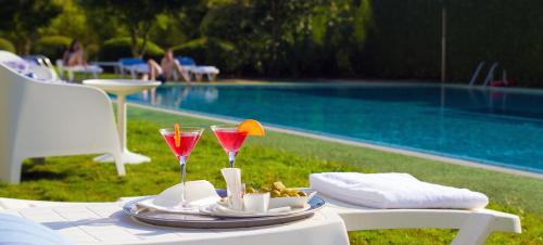 a table with two wine glasses on it next to a pool at Oca Puerta del Camino Hotel in Santiago de Compostela