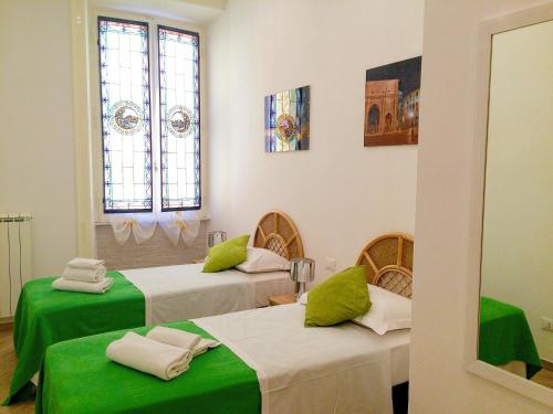 Cette chambre comprend 2 lits avec des draps verts et des fenêtres. dans l'établissement Sweet Roman Dream, à Rome