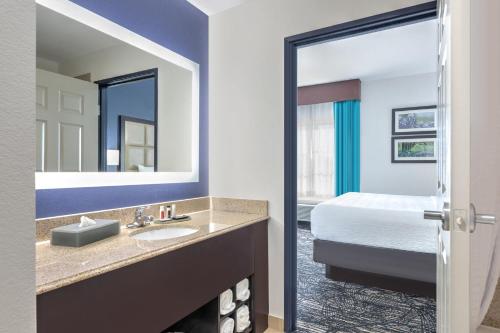 a bathroom with a sink and a bed and a mirror at La Quinta Inn and Suites by Wyndham Paris in Paris