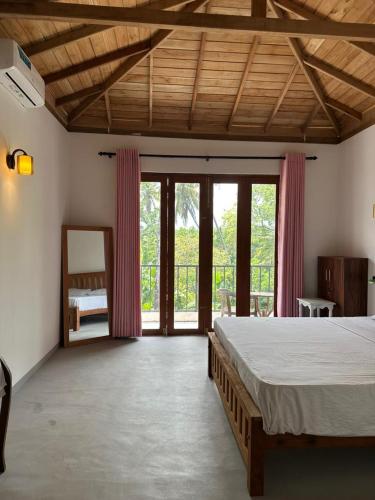 a bedroom with a large bed and sliding glass doors at Ruvee Villa in Weligama