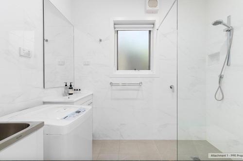 a white bathroom with a shower and a sink at Cromwell Lite in Cooma