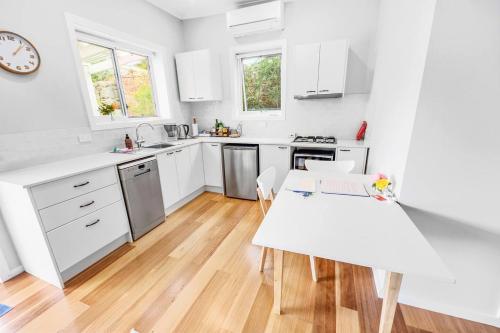 a kitchen with white cabinets and a white table at Cromwell Lite in Cooma