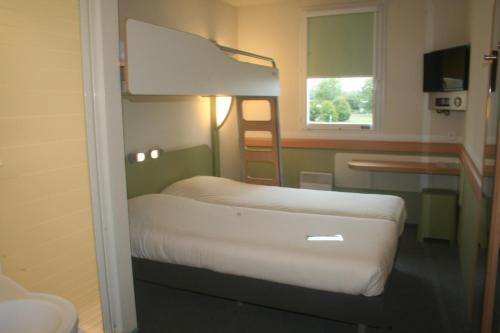 a small room with two beds and a window at ibis budget Niort - La Crèche in La Creche