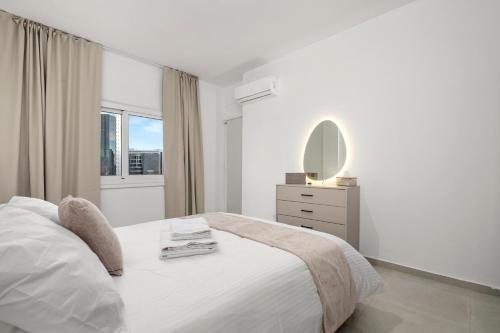a white bedroom with a bed and a mirror at Mnasiadou Suite 16 in Nicosia