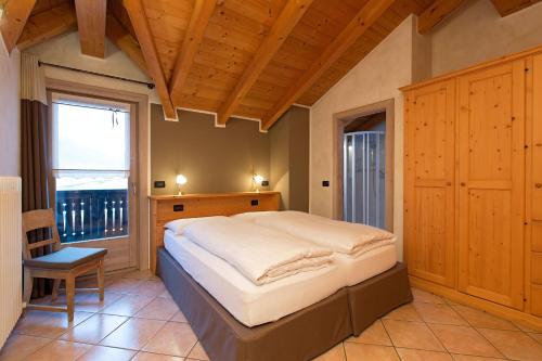 1 dormitorio con 1 cama grande y techo de madera en Al Chestelet, en Livigno