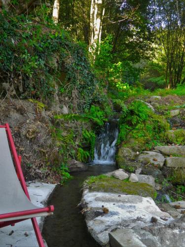 a red chair next to a small waterfall at Quinta Lamosa Agroturismo in Arcos de Valdevez