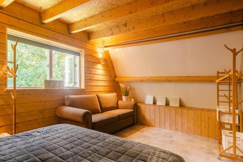 a bedroom with a bed and a chair and a window at Chalet Citola in Nuenen