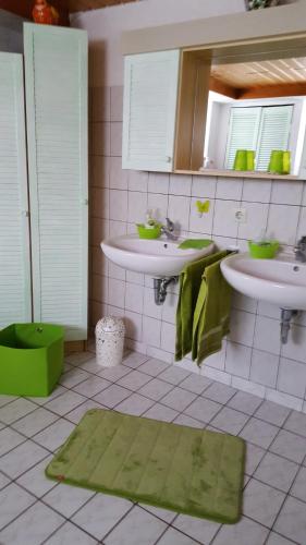 a bathroom with two sinks and a green rug at Gästehaus Baur in Kappel-Grafenhausen