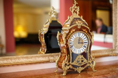 a gold clock sitting on a table in front of a mirror at Hotel Daniel in Basiano