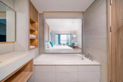 a bathroom with a bath tub and a bedroom at OceanView Alacarte Hạ Long in Ha Long