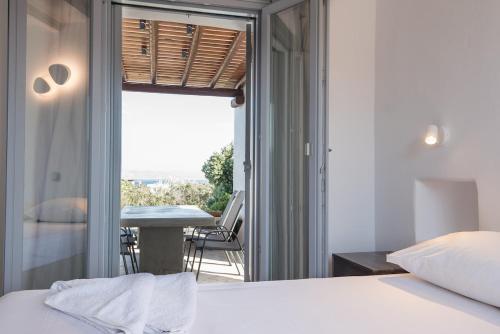 a bedroom with a bed and a table and a balcony at Seaview Villa Euterpe in Ambelas