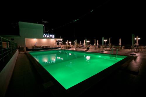 a swimming pool with green illumination at night at Oceanis Hotel in Kavala