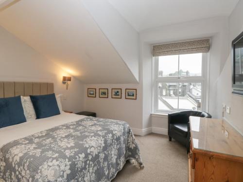 a bedroom with a bed and a desk and a window at Norwood House in Ambleside