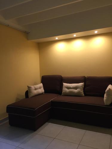 a brown couch in a room with two pillows on it at Gîtes La Simonière & Cars in Saint-François