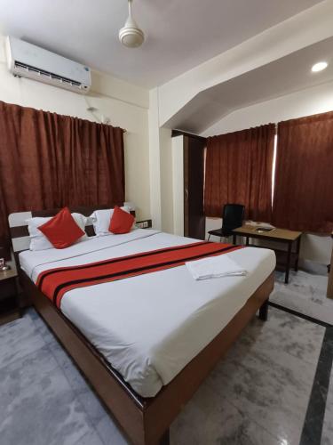 a bedroom with a large bed with red pillows at Welcome Regency in kolkata