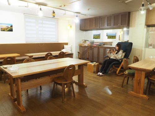 a woman sitting in a chair holding a baby in a room with tables at Guest House Moshiripa in Wakkanai