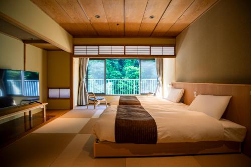 a bedroom with a large bed with a large window at Hakone Pax Yoshino in Hakone