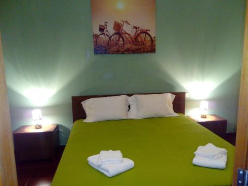 a bedroom with a green bed with two towels on it at Monte Família Ferreira in Vale de Açor