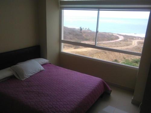 a bedroom with a purple bed and a large window at Ocean View in Playas