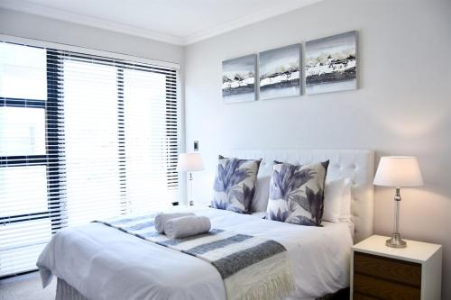 a white bedroom with a bed and a large window at Foreshore 2 Sea View Holiday accommodation in Langstrand