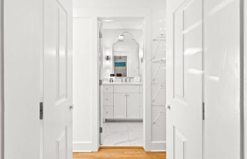 a white bathroom with white cabinets and a mirror at Sugar in Santa Rosa Beach