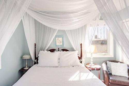 a bedroom with a white canopy bed with white pillows at Charming Victorian Home in Okotoks Elegant Comfort Modern Convenience in Okotoks