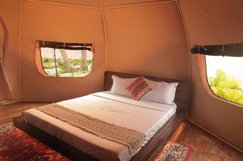 a bed in a small room with two windows at The Silkroad Mũi Né in Ấp Khánh Phước (1)