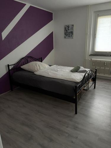 a bedroom with a bed with a purple and white wall at Red Dot Apartment Lucky in Kamen