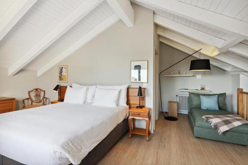 a bedroom with a large bed and a green chair at Stylish Duplex Apartment in Morges