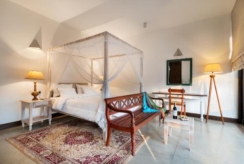 a bedroom with a canopy bed with a chair and a table at Casa18Villa in Kiribathgoda