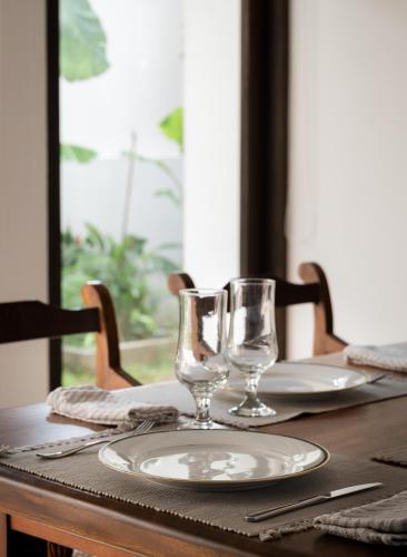 a table with a plate and two glasses on it at Casa18Villa in Kiribathgoda