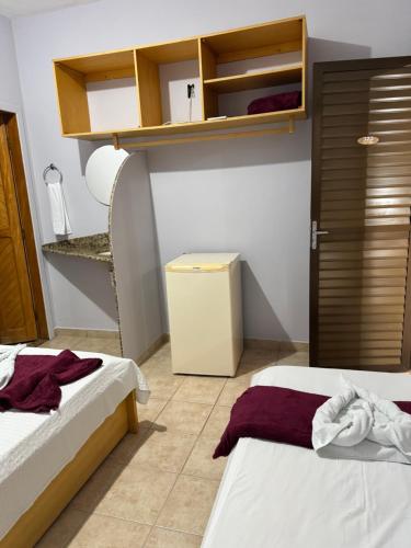 a room with two beds and a refrigerator at Pousada Refúgio da Ilha in São Mateus