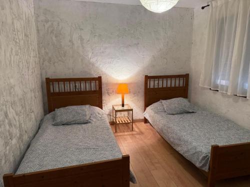 two beds in a room with a lamp on a table at La Caseta del Mas Valls in Rupiá