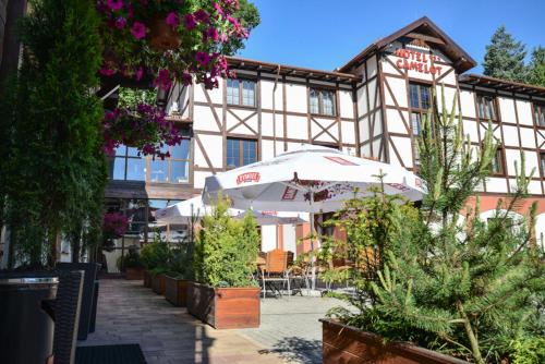 a building with an umbrella and plants in front of it at Hotel Camelot in Szczawno-Zdrój