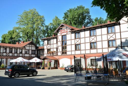 a car parked in front of a large building at Hotel Camelot in Szczawno-Zdrój