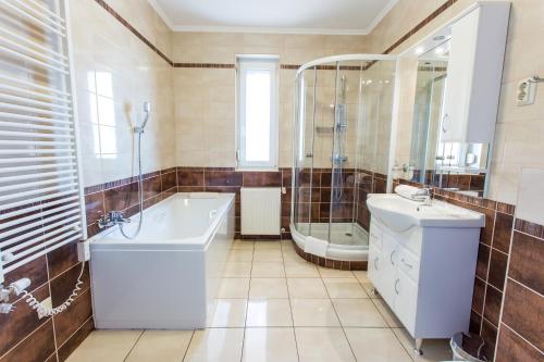 a bathroom with a tub and a shower and a sink at Luxury Apartment Hotel Siófok in Siófok