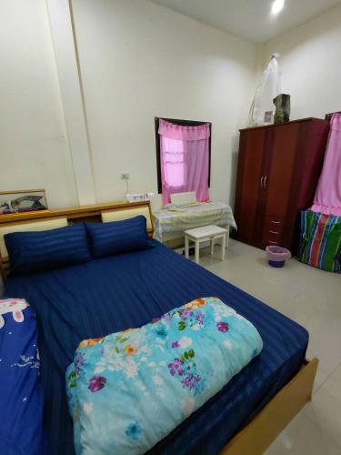 a bedroom with a bed with a blue comforter at ห้องว่างในบ้าน in Ban Bu Khi Lek